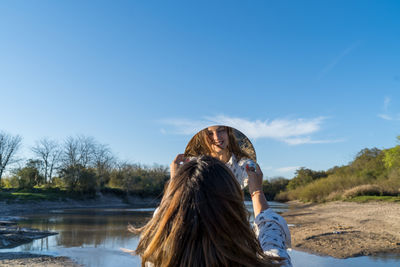 Rear view of woman against lake against sky