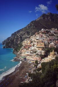 Scenic view of sea and buildings in town against sky