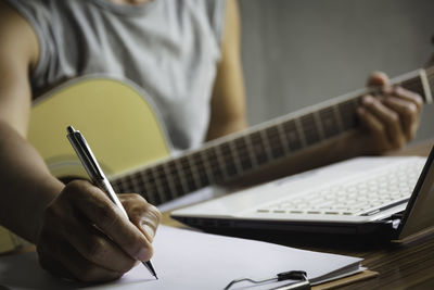 Midsection of man playing guitar on table