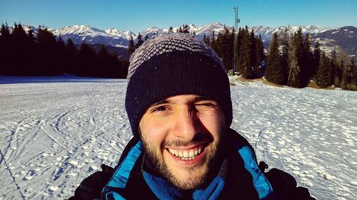 Portrait of happy man on snow covered field during sunny day