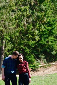 Loving young couple standing in forest during sunny day