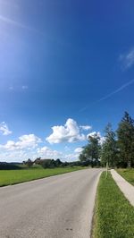 Empty road against blue sky on sunny day
