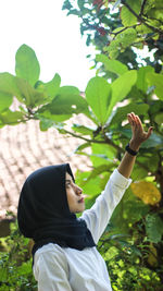 Side view of woman standing by trees