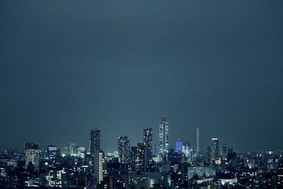 Illuminated buildings in city against sky at night