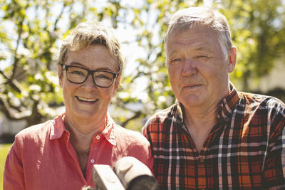 Portrait of happy senior couple with hammers while standing at yard