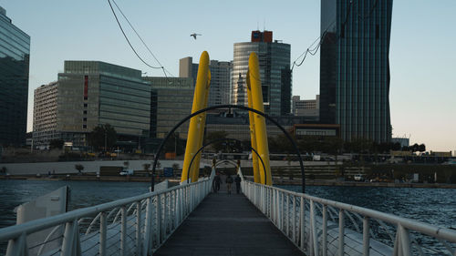 Bridge over river amidst buildings in city against sky