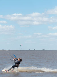 Woman surfing in sea against sky