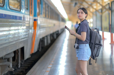 Full length of young woman standing at railroad station