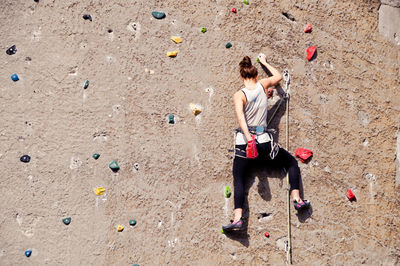 Rear view of woman climbing wall