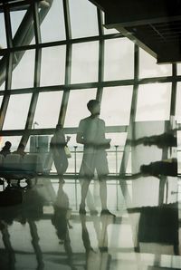 Reflection of silhouette people on glass window at airport