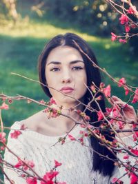 Portrait of young woman with pink flowers against blurred background