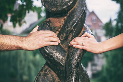 Cropped hands of people touching structure at public park