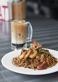 Close-up of mie goreng with iced coffee on table