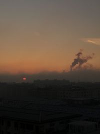 Smoke emitting from chimney against sky at sunset