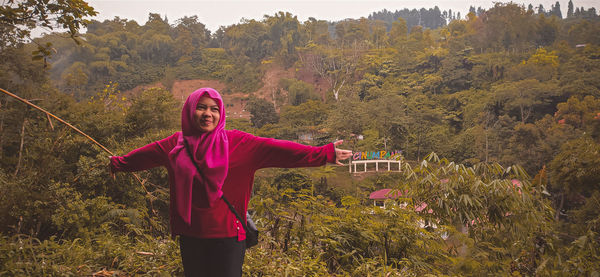 Woman with arms outstretched standing against mountain