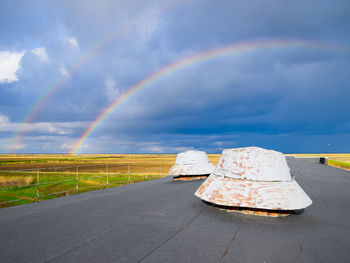 Rainbow over road against sky