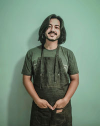 Portrait of hair dresser standing against green background