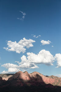 Low angle view of rocky mountain against blue sky
