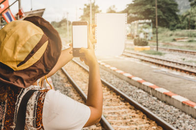 Rear view of woman sitting on railroad track