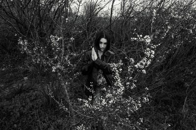 Portrait of young woman sitting on tree in forest