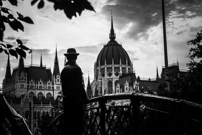 Rear view of man standing outside temple against sky in city