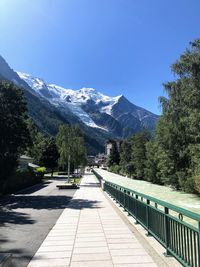 Road amidst trees and snowcapped mountains against sky