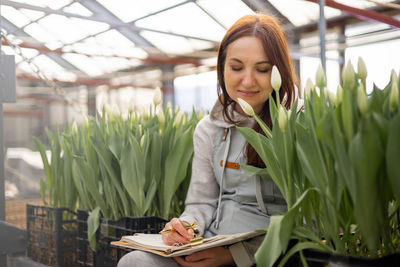 Portrait of young woman sitting by plants