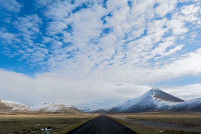 Road leading towards mountains against sky