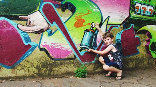 Optical illusion of boy holding bottle on graffiti wall
