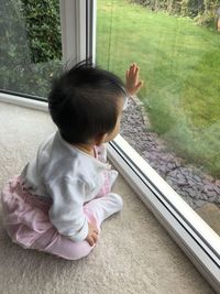 High angle view of baby girl looking through window at home