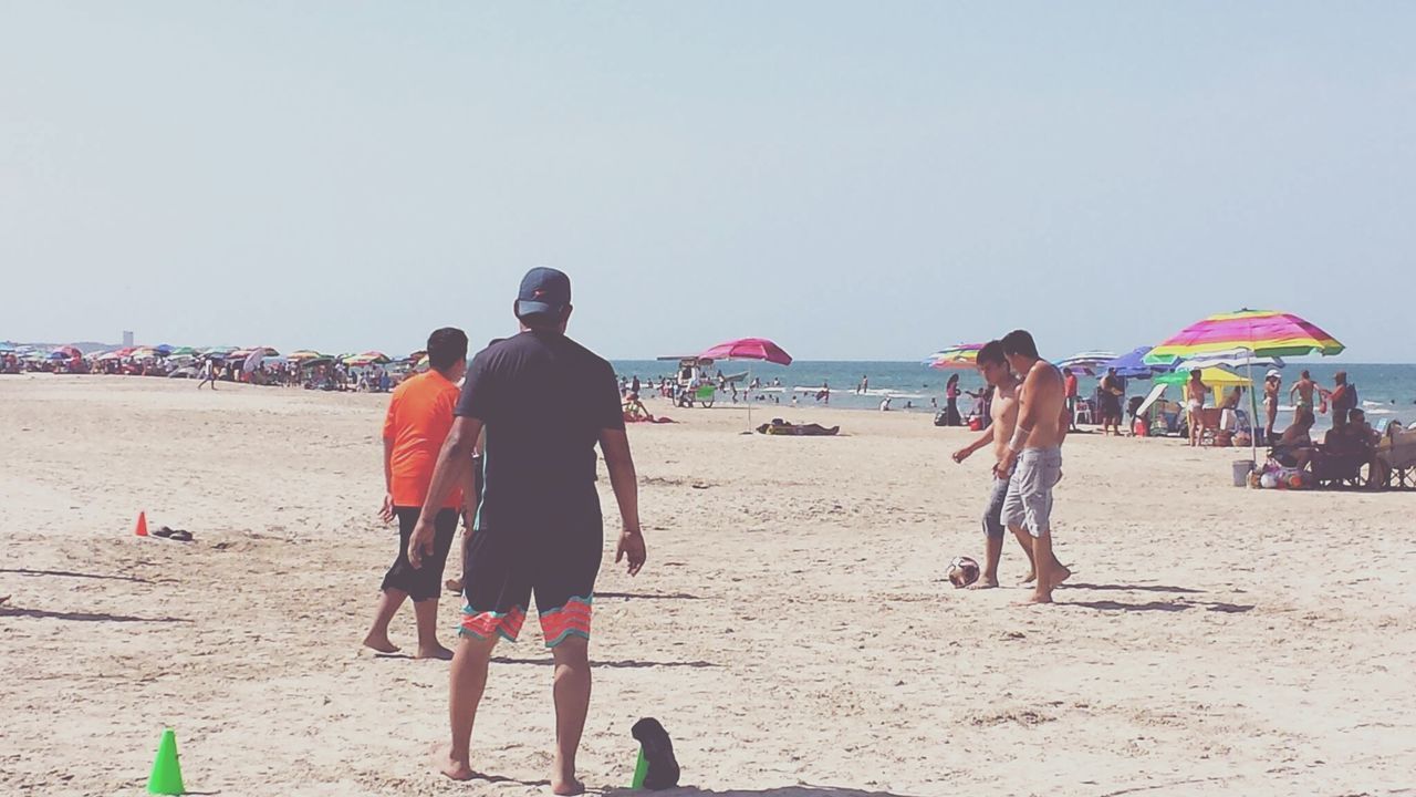 beach, sand, sea, shore, leisure activity, lifestyles, clear sky, water, men, large group of people, vacations, person, copy space, horizon over water, togetherness, rear view, full length, enjoyment, casual clothing