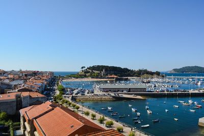 High angle view of city buildings by sea against clear sky