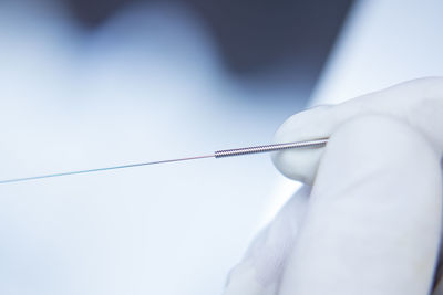 Cropped hand holding acupuncture needle in hospital