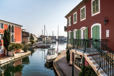 Sailboats in canal amidst buildings in city against sky