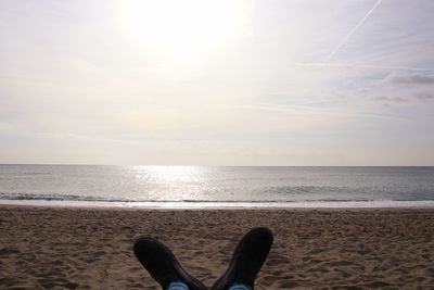 Low section of person on beach against sky