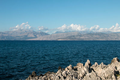 Scenic view of sea and mountains against blue sky