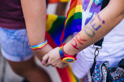 Midsection of lesbian couple holding hands during protest