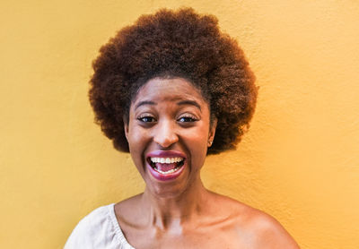 Portrait of a smiling young woman against yellow wall