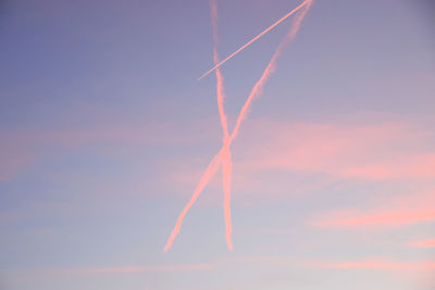 Low angle view of vapor trails against sky during sunset