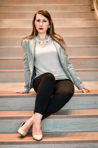 Business woman dressed in business clothes poses on staircase