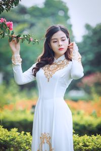 Portrait of smiling young woman standing against plants