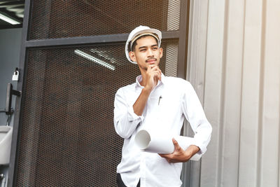 Thoughtful engineer wearing hardhat looking away outdoors