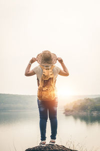 Full length of boy standing by lake against clear sky