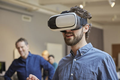 Male professional using virtual reality simulator against colleagues at creative office