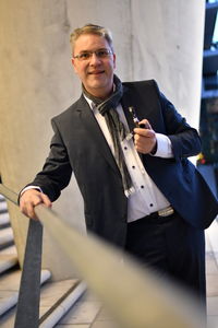 Portrait of businessman holding smoking pipe while standing on staircase