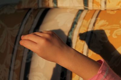 Cropped hand of child gesturing by sofa at home