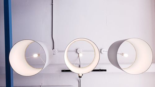 Illuminated light bulbs hanging on white wall