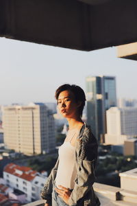 Portrait of woman standing against buildings in city