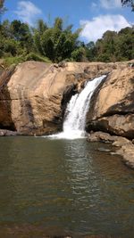 Scenic view of waterfall in forest against sky