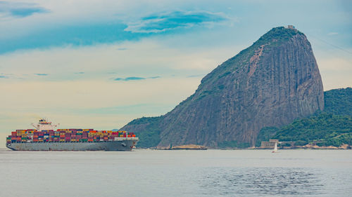 Photo of sugarloaf mountain with a cargo ship passing in front of it in guanabara bay